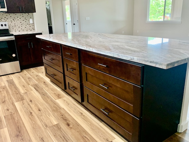 kitchen featuring tasteful backsplash, light hardwood / wood-style flooring, stainless steel stove, and a kitchen island