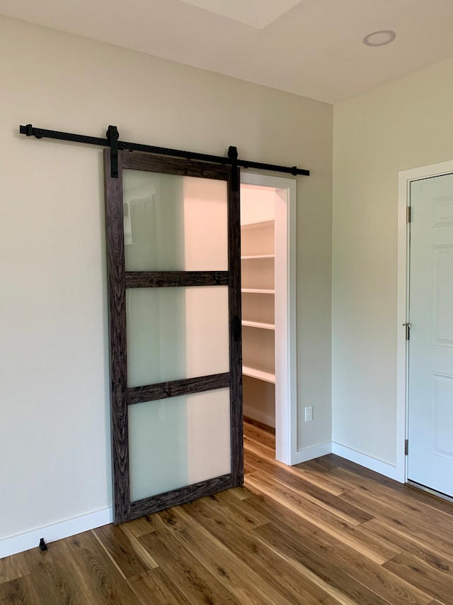 unfurnished room with a barn door and hardwood / wood-style flooring