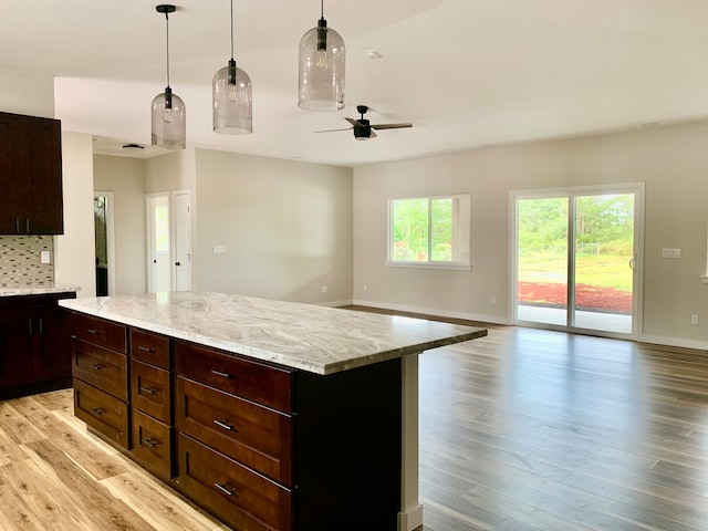 kitchen featuring decorative backsplash, a center island, light wood-type flooring, and hanging light fixtures