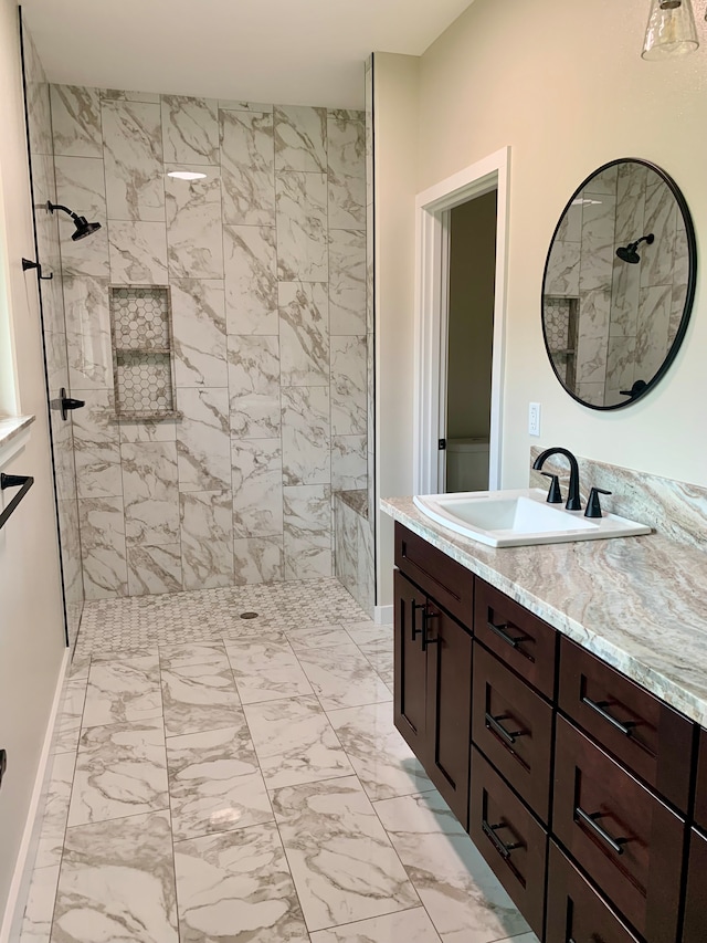 bathroom featuring tiled shower and vanity