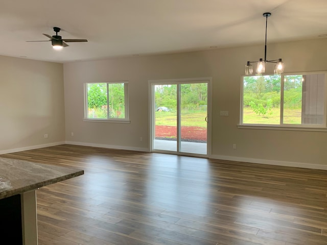 interior space featuring ceiling fan with notable chandelier and dark wood-type flooring