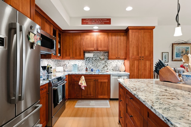 kitchen featuring light stone countertops, appliances with stainless steel finishes, tasteful backsplash, light hardwood / wood-style flooring, and hanging light fixtures