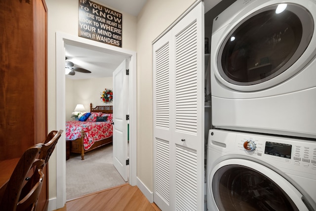 washroom with ceiling fan, light hardwood / wood-style floors, and stacked washer / dryer