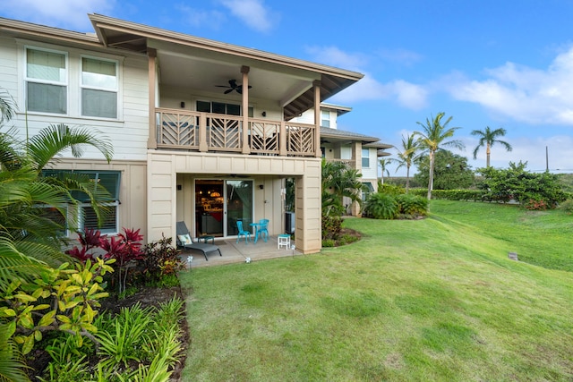 back of property featuring ceiling fan, a balcony, and a yard