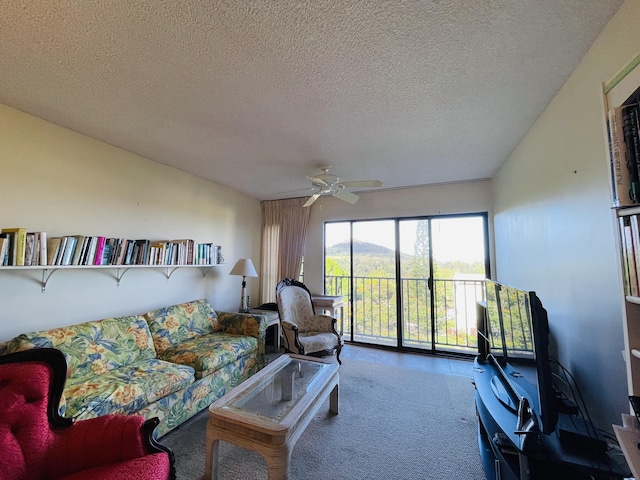 living room featuring ceiling fan, carpet floors, and a textured ceiling