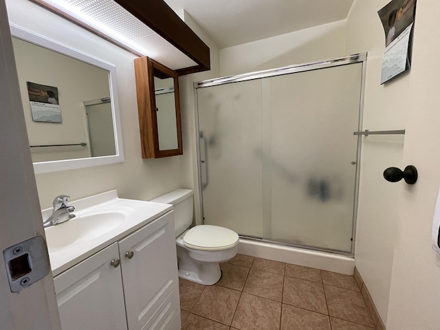 bathroom featuring toilet, vanity, tile patterned floors, and a shower with shower door