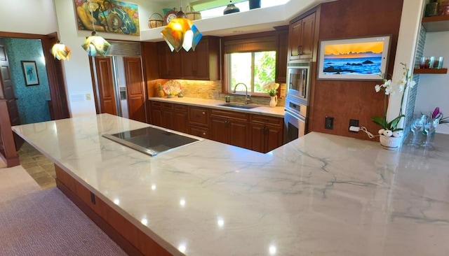 kitchen featuring sink, hanging light fixtures, stainless steel appliances, tasteful backsplash, and light stone counters