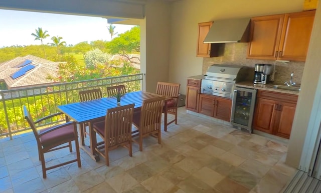 kitchen with backsplash, sink, wall chimney exhaust hood, and beverage cooler