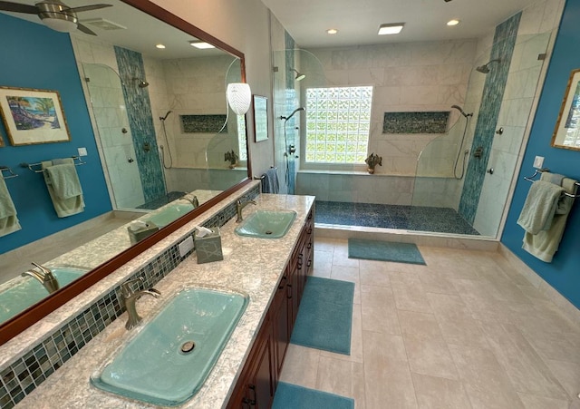 bathroom with tasteful backsplash, tile patterned floors, a tile shower, vanity, and ceiling fan