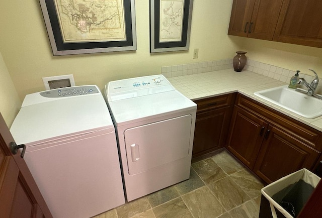 washroom featuring washing machine and clothes dryer, sink, and cabinets