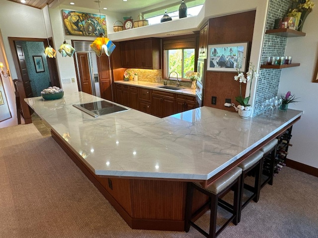 kitchen with sink, kitchen peninsula, pendant lighting, a kitchen bar, and black electric cooktop