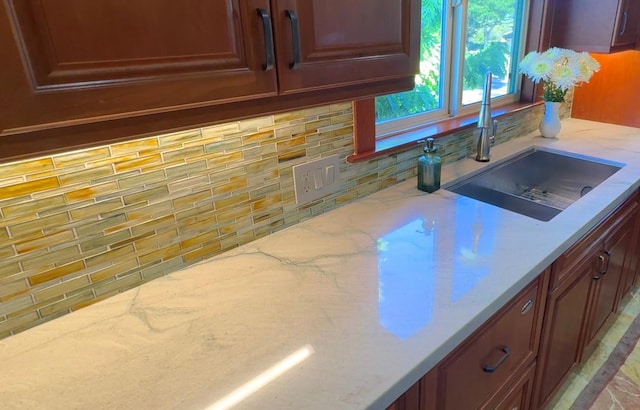 kitchen featuring light stone countertops, sink, and tasteful backsplash