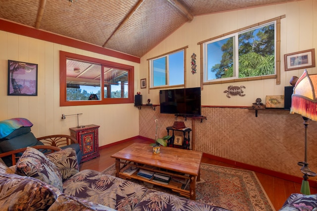 living room with wooden walls, plenty of natural light, wood-type flooring, and lofted ceiling