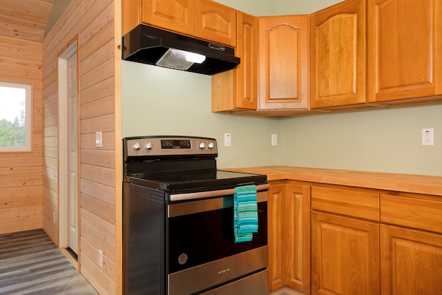 kitchen with stainless steel electric range oven, wooden walls, and dark wood-type flooring