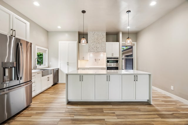 kitchen featuring decorative light fixtures, a kitchen island, white cabinetry, and stainless steel appliances