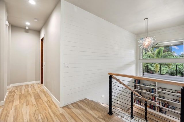 hallway featuring a chandelier and light hardwood / wood-style flooring