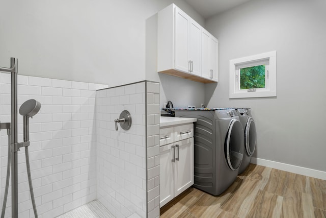 laundry room featuring washing machine and dryer, light hardwood / wood-style flooring, and cabinets