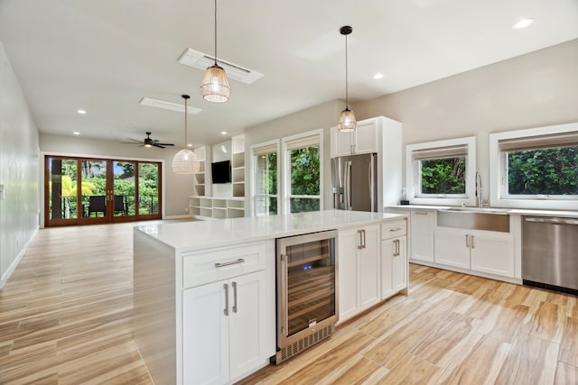 kitchen with appliances with stainless steel finishes, a wealth of natural light, white cabinets, and wine cooler