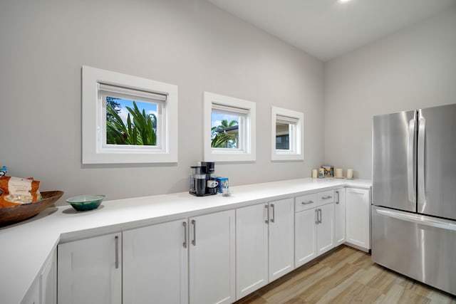 kitchen featuring stainless steel refrigerator, white cabinetry, and light wood-type flooring