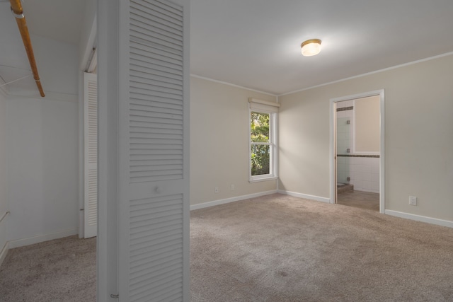 unfurnished bedroom featuring connected bathroom, light colored carpet, a closet, and ornamental molding