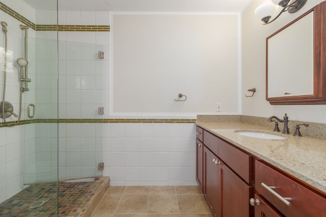 bathroom with tile patterned floors, vanity, a shower with shower door, and tile walls