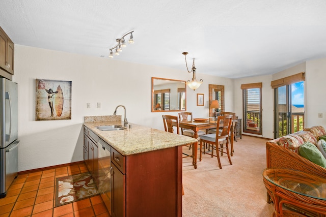 kitchen with pendant lighting, sink, light stone countertops, appliances with stainless steel finishes, and light tile patterned flooring