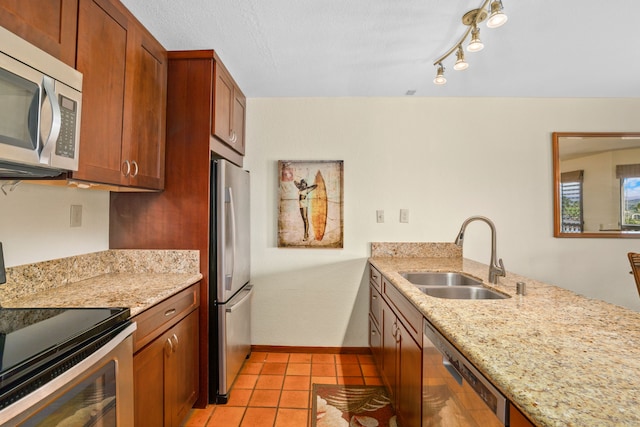 kitchen with light stone countertops, sink, light tile patterned floors, and stainless steel appliances