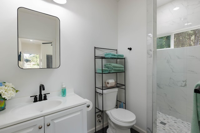 bathroom featuring a tile shower, vanity, and toilet