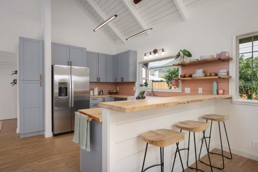 kitchen with a kitchen breakfast bar, stainless steel fridge, high vaulted ceiling, and wood counters