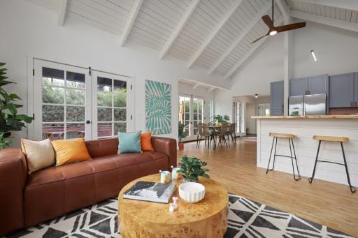 living room featuring french doors, ceiling fan, beam ceiling, high vaulted ceiling, and light hardwood / wood-style floors