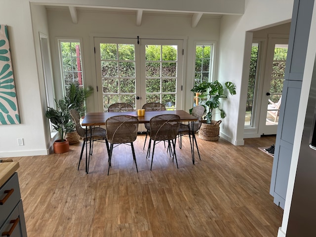 dining room with beamed ceiling, a healthy amount of sunlight, and hardwood / wood-style floors