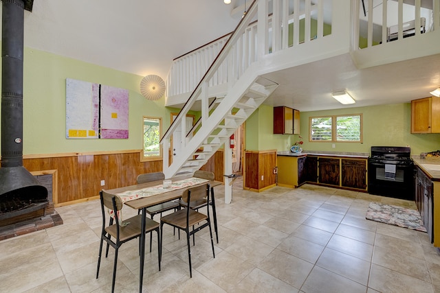 dining area with wood walls, plenty of natural light, light tile patterned flooring, and a wood stove