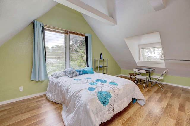 bedroom with multiple windows, wood-type flooring, and lofted ceiling