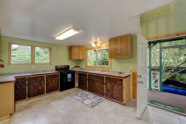 kitchen featuring light tile patterned floors, a textured ceiling, black range oven, and sink