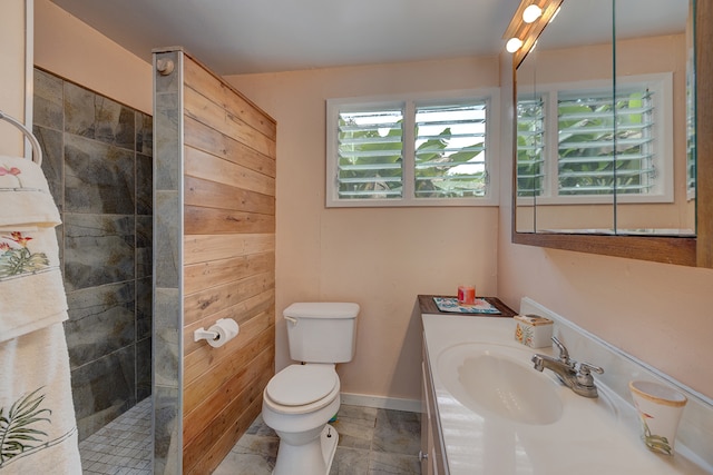 bathroom featuring a tile shower, vanity, toilet, and wood walls