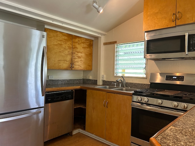 kitchen with sink, hardwood / wood-style floors, vaulted ceiling, and appliances with stainless steel finishes