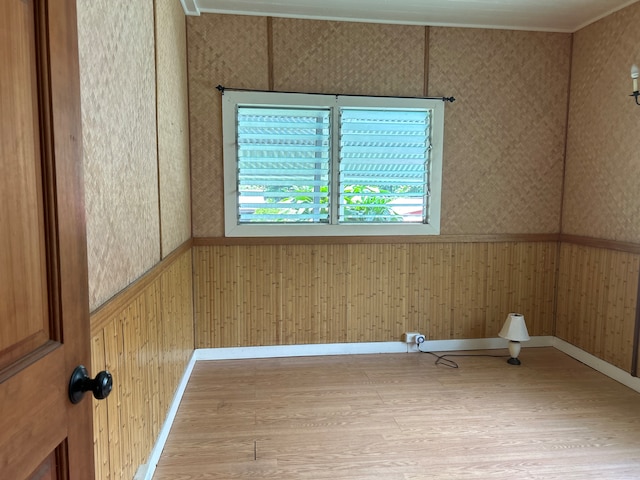 spare room with light wood-type flooring and wood walls