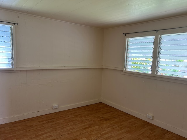 empty room featuring hardwood / wood-style floors, a wealth of natural light, and ornamental molding