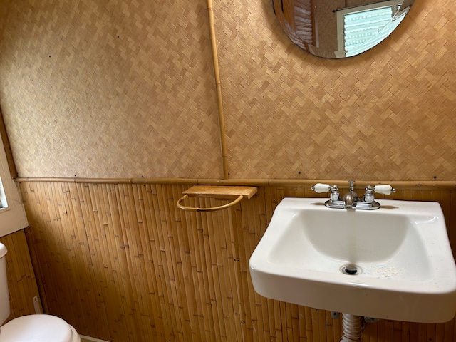 bathroom featuring wood walls, sink, and toilet