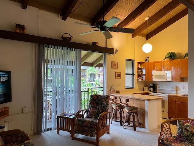 kitchen featuring hanging light fixtures, kitchen peninsula, light colored carpet, white appliances, and a breakfast bar area