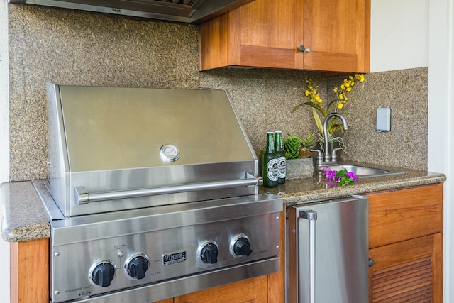 details featuring tasteful backsplash, stainless steel refrigerator, and sink