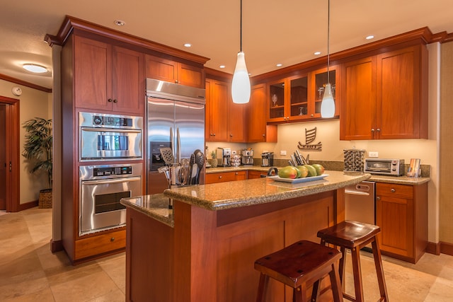 kitchen with appliances with stainless steel finishes, a breakfast bar, decorative light fixtures, dark stone countertops, and a kitchen island