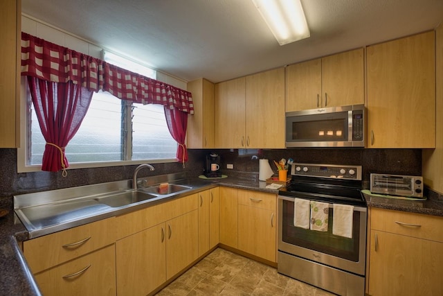 kitchen with decorative backsplash, appliances with stainless steel finishes, light brown cabinets, and sink