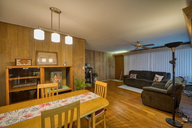 dining room with wooden walls, ceiling fan, and hardwood / wood-style flooring