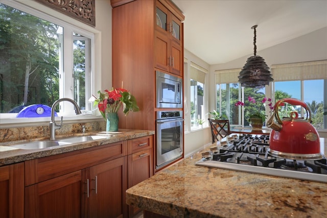 kitchen featuring light stone countertops, sink, hanging light fixtures, lofted ceiling, and appliances with stainless steel finishes