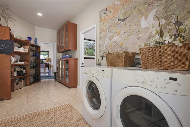 laundry room with cabinets, light tile patterned floors, and washing machine and clothes dryer