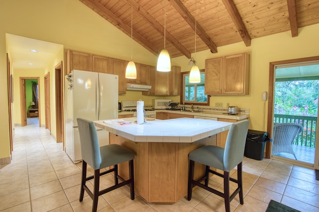 kitchen with beam ceiling, tile counters, light tile patterned floors, white appliances, and a kitchen island