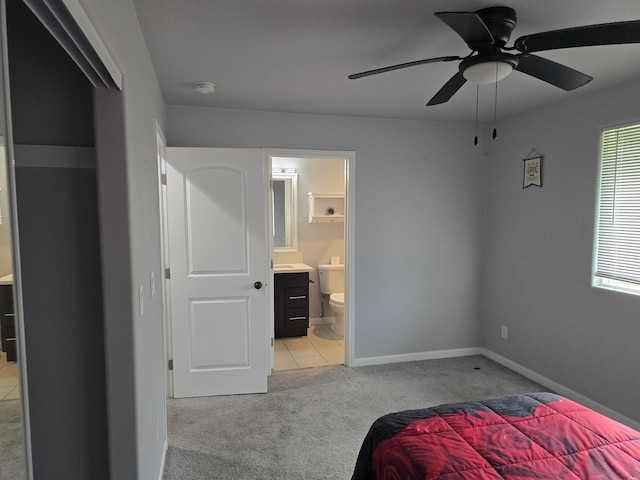 bedroom with a ceiling fan, light carpet, baseboards, and ensuite bathroom