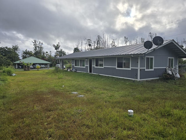 rear view of house with metal roof and a yard