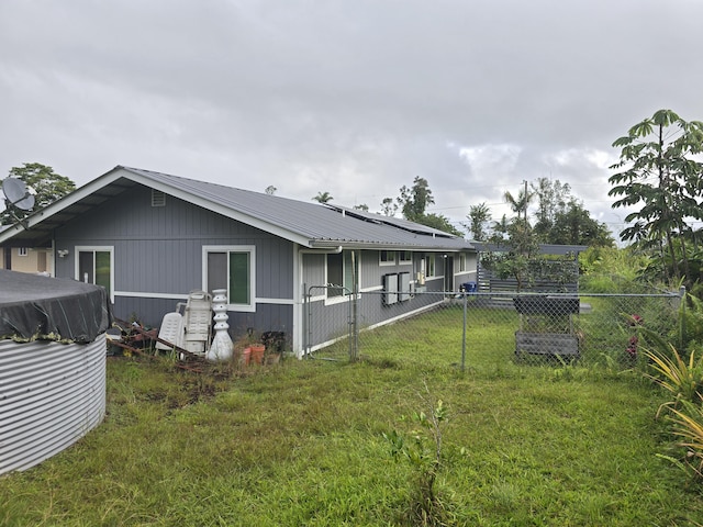 exterior space with solar panels, fence, metal roof, and a lawn